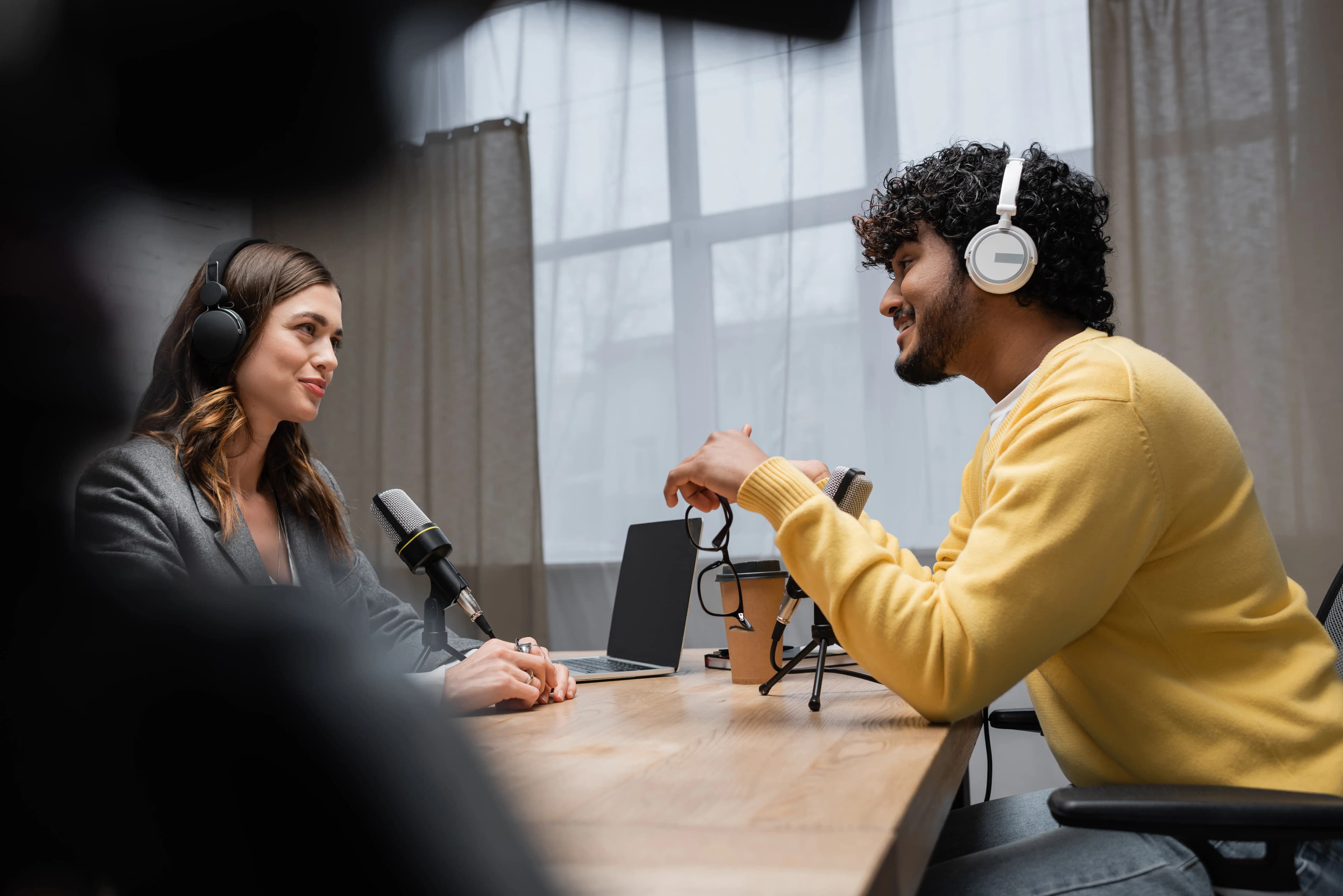Smiling podcaster with headphones creating content while building successful fashion merchandise business
