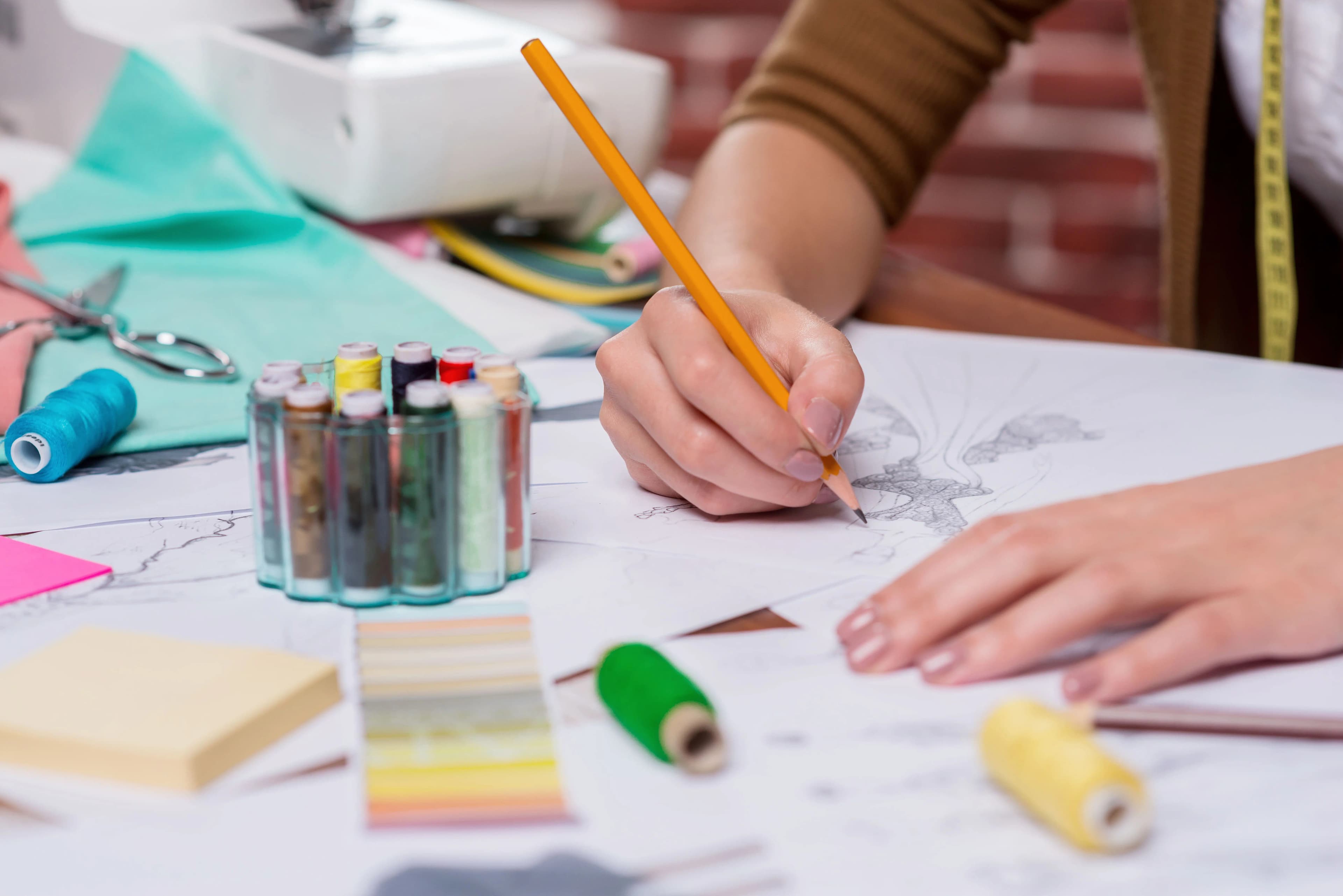 Designer sketching technical fashion drawings, the craft behind Plucky Reach tech packs and production